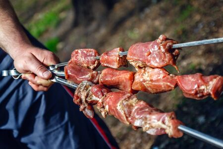 man holds in his hands a skewer with raw meat, life style.の写真素材