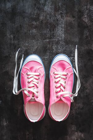 purple-pink-lilac sneakers with untied laces on a dark concrete background. Copy space. View from aboveの写真素材