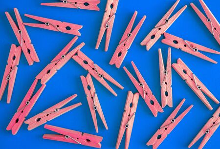 Wooden red clothespins are scattered on a blue-cyan-green background. Frame of clothespins. View from above. Copy space. Flat lay. The concept is natural, eco-friendly.の写真素材