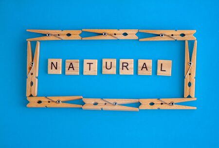 Wooden clothespins are scattered on a white and blue background with the words eco and natural. View from above. Copy space. Flat lay. The concept is natural, eco-friendly.の写真素材