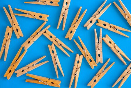 Wooden yellow clothespins are scattered on a cyan-blue background. Frame of clothespins. View from above. Copy space. Flat lay. The concept is natural, eco-friendly.の写真素材
