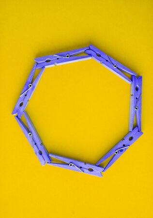Round frame of colored wooden clothespins on a color bright yellow-green background. View from above. Copy space. Flat lay. The concept is natural, eco-friendly.の写真素材