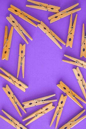 Background and frame of wooden yellow clothespins on lilac-purple background. View from above. Copy space. The concept of naturalness and eco.の写真素材
