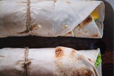 Lavash rolls with meat, vegetables and cheese served with green. Lettuce salad on rustic wooden table. Healthy breakfast concept. Greek traditional foodの写真素材