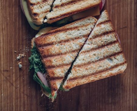 Two sandwiches on a wooden background, top view. Stack of panini with ham, cheese and lettuce sandwich on a cutting board.の写真素材