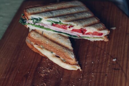 Two sandwiches on a wooden background, top view. Stack of panini with ham, cheese and lettuce sandwich on a cutting board.の写真素材