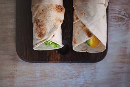 Lavash rolls with meat, vegetables and cheese served with green. Lettuce salad on rustic wooden table. Healthy breakfast concept. Greek traditional foodの写真素材