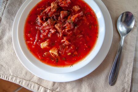 traditional Ukrainian-Russian tomato borscht soup with sour cream in a white plate on the table. View from aboveの写真素材