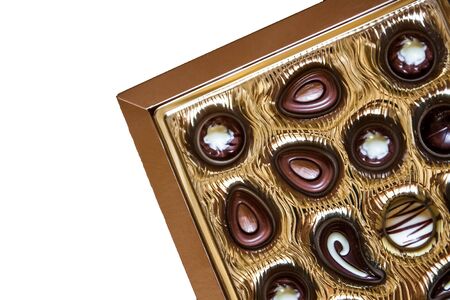 Chocolate candies of different shapes in a gold box,View from above. Isolated on a white background. Close-up.の写真素材