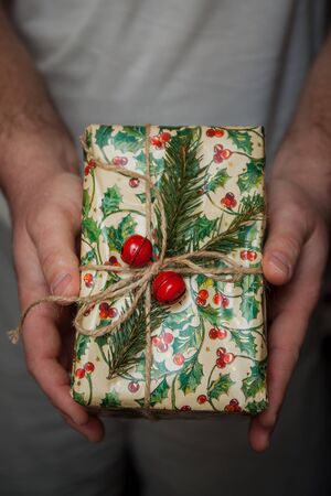 Wrapped New Year's gifts with fir and cones and bells in hands. Life style.の写真素材