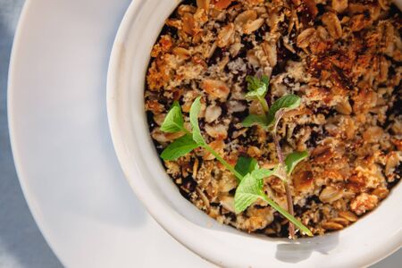 baked oat-blueberry crumble with mint in a white and blue plate on a rustic linen tablecloth. Save the space, top view. The concept of healthy proper nutrition for breakfast, vegetarianismの写真素材