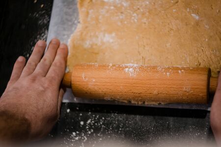 baker's hands roll ginger dough on a dark background. Close-up, soft focus. Side view, top view. Copy spaceの写真素材