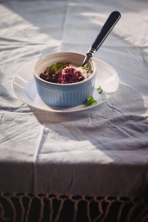 baked oat-blueberry crumble with mint in a white and blue plate on a rustic linen tablecloth. Save the space, top view. The concept of healthy proper nutrition for breakfast, vegetarianismの写真素材