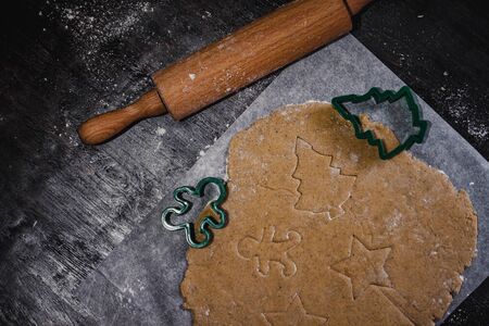 cut out gingerbread cookie in the form of a Christmas tree, star, little man, hearts from raw dough...