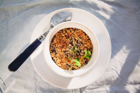 baked oat-blueberry crumble with mint in a white and blue plate on a rustic linen tablecloth. Save the space, top view. The concept of healthy proper nutrition for breakfast, vegetarianismの写真素材
