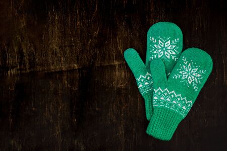 a pair of blue-green knitted mittens on a dark blue-green-brown wooden vintage background, copy space.の写真素材