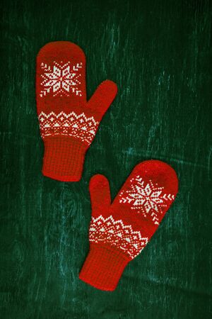 a pair of red-pink-lilac-magenta purple knitted mittens on a dark blue-green-brown wooden vintage background, copy space.の写真素材