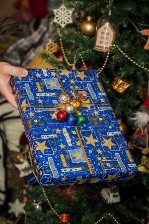 Wrapped gifts under the festively decorated Christmas tree in the hands. Life style.の写真素材