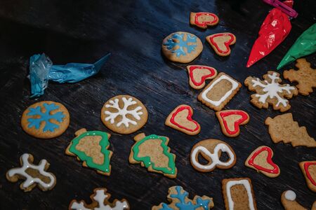 decorate Christmas gingerbread cookies using colored glaze on a dark wooden table, top view.の写真素材