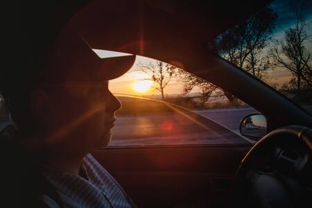 man driving a car at sunset-dawn, close-up, blur. Concept, road trips and travel, freedom of movement.の写真素材