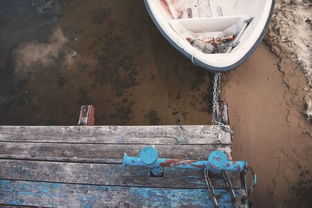 Old boat on an old wooden blue wharf on a river-lake. Top view, close up.の写真素材
