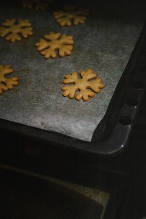 to get gingerbread cookies in the form of snowflakes from a oven mittの写真素材