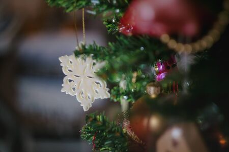 Christmas toys in the form of a blue-red-white vintage star-snowflake on a Christmas decorated Christmas tree. Close-upの写真素材
