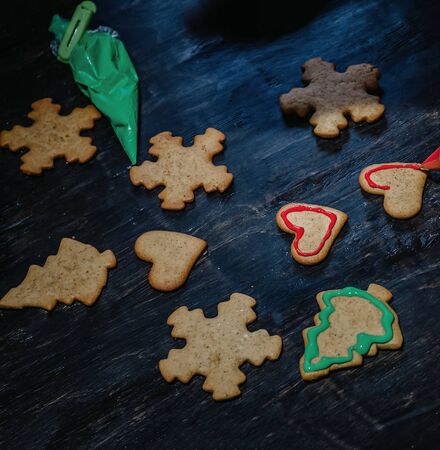 decorate Christmas gingerbread cookies using colored glaze on a dark wooden table, top view.の写真素材