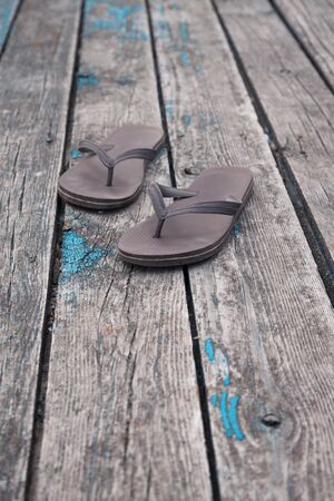 brown flip flops slippers on old wooden deck mooring background.の写真素材