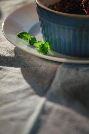 baked oat-blueberry crumble with mint in a white and blue plate on a rustic linen tablecloth. Save the space, top view. The concept of healthy proper nutrition for breakfast, vegetarianismの写真素材