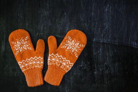 a pair of yellow orange knitted mittens on a dark blue-green-brown wooden vintage background, copy space.の写真素材