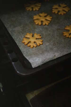 to get gingerbread cookies in the form of snowflakes from a oven mittの写真素材