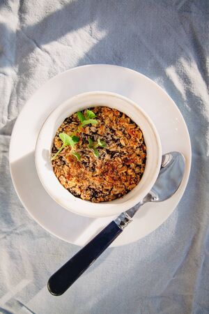 baked oat-blueberry crumble with mint in a white and blue plate on a rustic linen tablecloth. Save the space, top view. The concept of healthy proper nutrition for breakfast, vegetarianismの写真素材