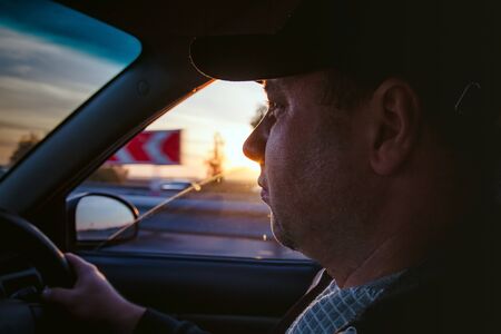 man driving a car at sunset-dawn, close-up, blur. Concept, road trips and travel, freedom of movement.の写真素材