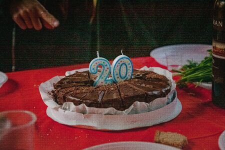 chocolate cake with candles 20 years on a red festive table.の写真素材
