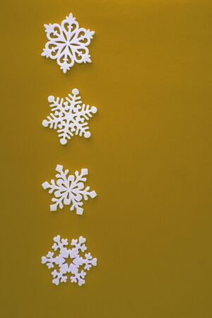 Christmas holidays composition, top view white snowflakes decoration on yellow background with copy space for text. Flat lay. Winter, postcard template.の写真素材