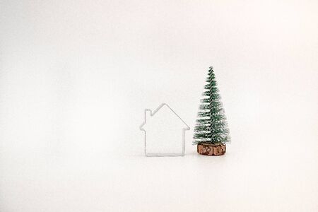 miniature snow-covered Christmas tree and a simple house isolated on white background.の写真素材