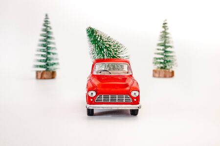 miniature red car in the back carries a Christmas tree on a white isolated background, top view. Save the space. Concept, festive Christmas mood, gift delivery. The trendの写真素材