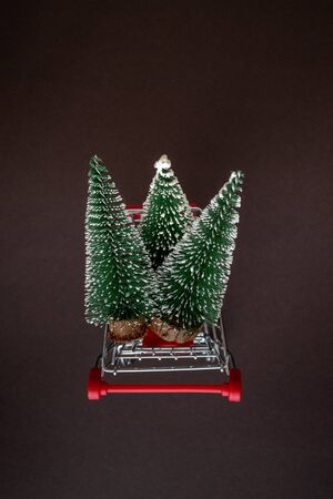 Top view of a grocery cart with snowy Christmas trees on a dark background with copy space for text. The apartment was lying. Winter, postcard templateの写真素材