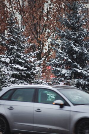 a car in motion rides along a tall building on a winter road in snow.の写真素材