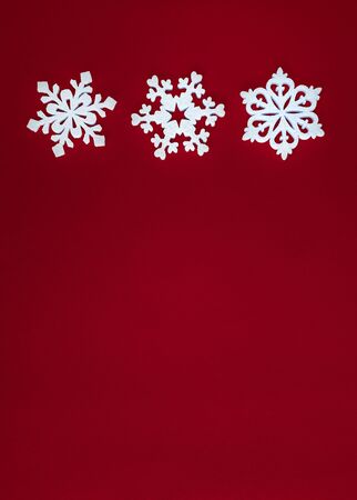 Christmas holidays composition, top view white snowflakes decoration on red background with copy space for text. Flat lay. Winter, postcard template.の写真素材