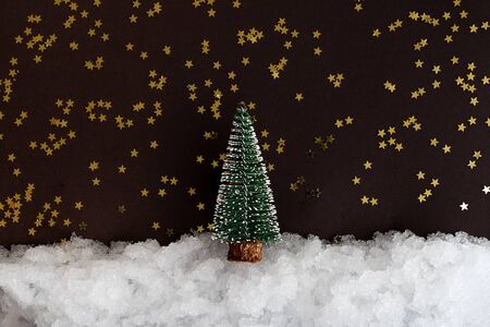 Christmas miniature on snow and dark background with shiny stars with copy space. Christmas composition, postcard template.の写真素材