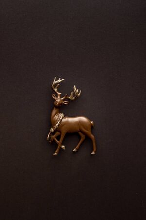 Miniature deer on a dark background with copy space. Christmas composition, postcard template. Flat lay.の写真素材