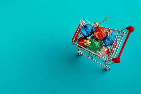 Grocery cart with Christmas balls toys on a blue-green simple background. Flat lay. Save the space. Postcard Template.の写真素材