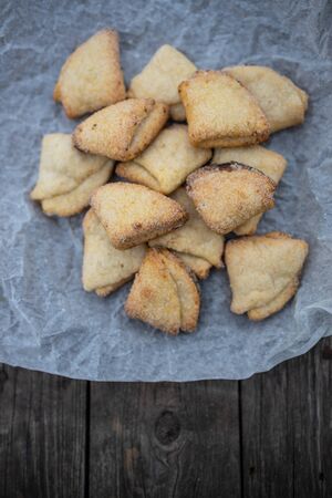 Cottage cheese shortbread triangles on white parchment on an old dark wooden background