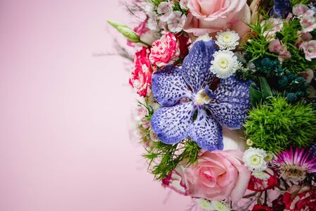 stylish trendy delicate bouquet with a variety of spring flowers, roses, orchids in a round box on a pink background. Copy spaceの写真素材