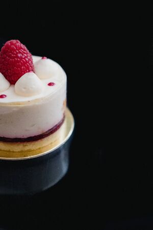 Luxury white cheesecake mousse cake decorated with fresh raspberries on a dark background. Flat lay. Close-up. Copy spaceの写真素材