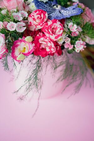 stylish trendy delicate bouquet with a variety of spring flowers, roses, orchids in a round box on a pink background. Copy space.の写真素材