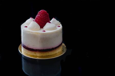 Luxury white cheesecake mousse cake decorated with fresh raspberries on a dark background. Flat lay. Close-up. Copy spaceの写真素材