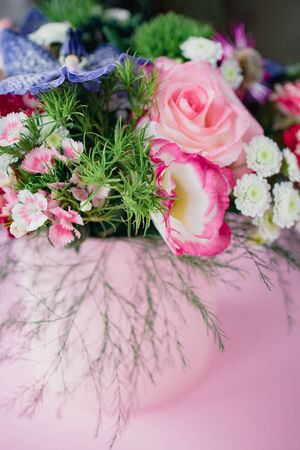 stylish trendy delicate bouquet with a variety of spring flowers, roses, orchids in a round box on a pink background. Copy space.の写真素材